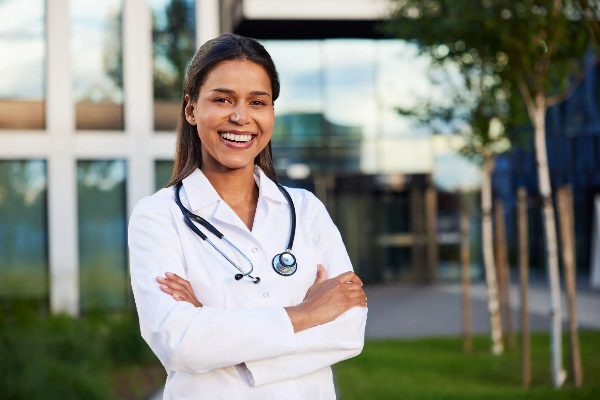 Médica sonriendo frente a una institución de salud